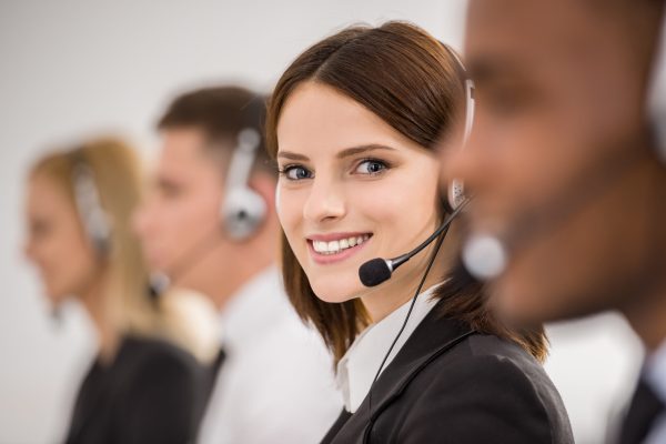 Call centre workers working in line with their headsets. Side view.